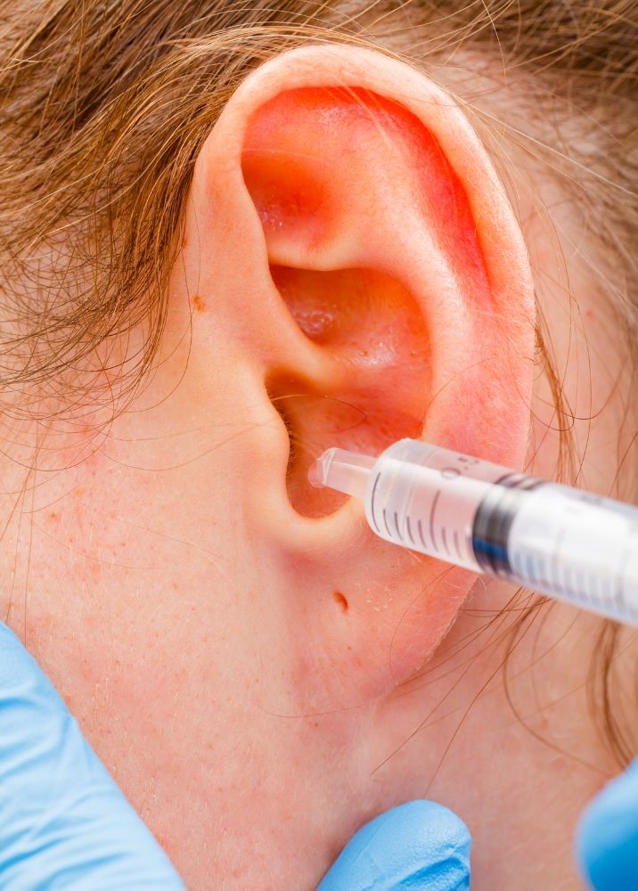 Image of a woman's ear with a syringe